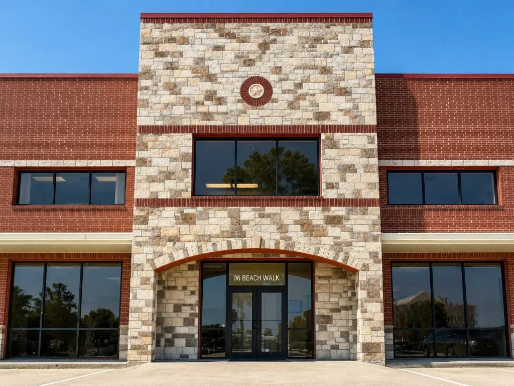 Straight-on exterior of Beach Walk Office Suites at 96 Beach Walk Blvd., showing the stone entrance tower and brick wings