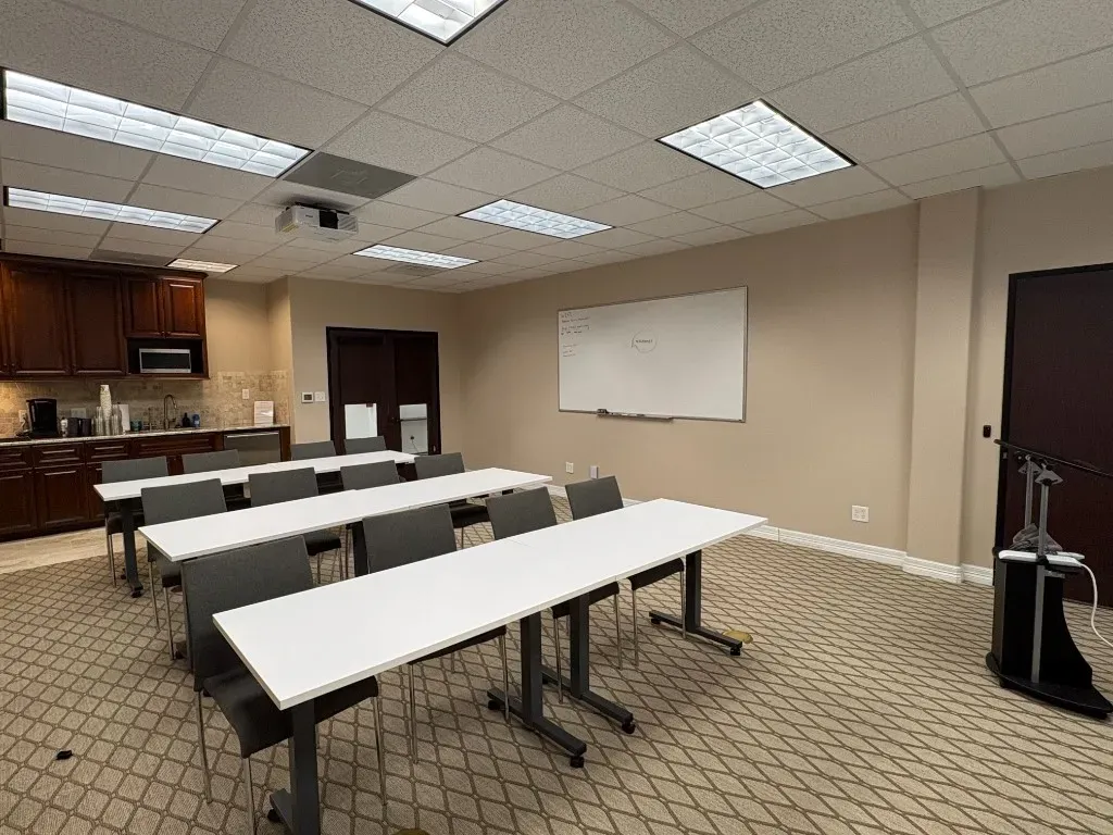Training room with classroom-style tables, projector, and whiteboard