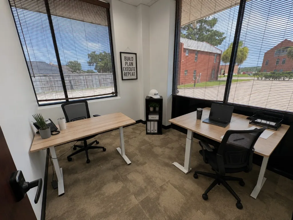 Bright private window office with two standing desks and ergonomic chairs