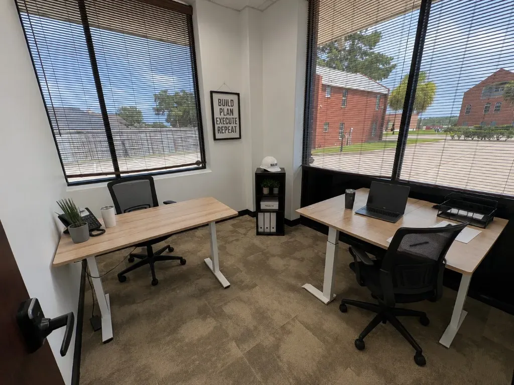 Bright private window office with two standing desks and ergonomic chairs